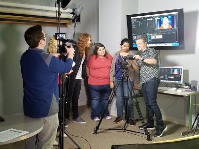 A male instructor showing a group of students how to use camera equipment